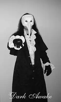 Shelmerdine trägt ein Rüschenhemd und eine venezianische Maske