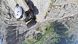 Kletterer am Daubenhorn im Leukerbad-Klettersteig am Aufstieg der Schlüsselstelle Via Konst in 2900&nbsp;m Höhe, Blick herab auf das 1,4&nbsp;km darunter gelegene Leukerbad