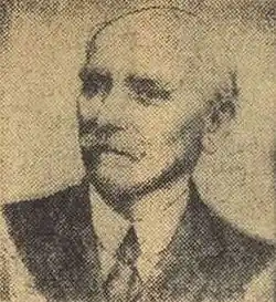 Nach links schauender älterer Mann im dunklem Anzug, weißem Hemd und Krawatte von vorn ab Brustkorb in schwarzweiß.