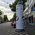 Litfaßsäule in der Form des beworbenen Antitranspirants (Düsseldorf, Steinstraße, Juli 2023)