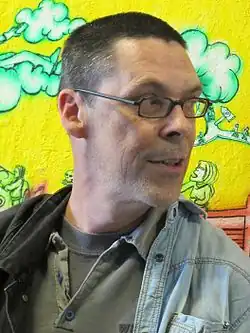 Porträt von Dominik Dombrowski vor einer Wand mit Graffiti