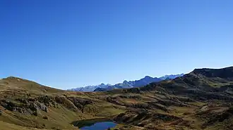 In der Bildmitte das Sünser Joch (1903 m ü. A.) an der Gemeindegrenze zwischen Dornbirn und Damüls. Links der Hübsche Bühel 2032 m ü. A.), rechts das Portlahorn (2010 m.ü.A.). In der Mitte unten, der Sünsersee, dahinter die Damülser Berge.