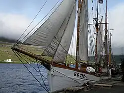 Das Bild zeigt ein Schiff mit einer hölzernen Spiere am Bug