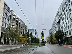 Foto einer von größeren Gebäudekomplexen gesäumte Straße, in der Mitte eine Straßenbahnspur
