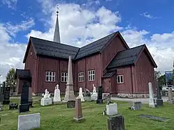 Foto einer Holzkirche mit Grabsteinen im Vordergrund