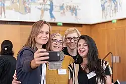 vier Frauen stehen Arm-in-Arm und machen eine Selfie