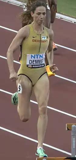 Eileen Demes läuft auf eine Hürde zu. Sie trägt das einteilige goldene Nationaltrikot mit der roten Aufschrift Germany.