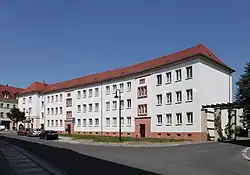 Der leicht geschwungene Gebäudeteil Eckartstraße 25–27 setzt am linken Bildrand an die Straßenrandbebauung Leipziger Straße (Hausnummern 58–61) an. (2012)