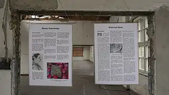 Ausstellungstafeln zeigen Biografien zu in Ravensbrück inhaftierten Frauen. Die Tafeln sind an einer Wand aufgehängt und zeigen auch Abbildungen.