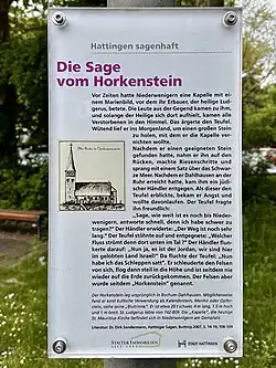 Inschrift: Vor Zeiten hatte Niederwenigern eine Kapelle mit einem Marienbild, vor dem ihr Erbauer, der heilige Ludgerus, betete. Die Leute aus der Gegend kamen zu ihm, und solange der Heilige sich dort aufhielt, kamen alle Verstorbenen in den Himmel. Das ärgerte den Teufel. Wütend lief er ins Morgenland, um einen großen Stein zu holen, mit dem er die Kapelle vernichten wollte. Nachdem er einen geeigneten Stein gefunden hatte, nahm er ihn auf den Rücken, machte Riesenschritte und sprang mit einem Satz über das Schwarze Meer. Nachdem er Dahlhausen an der Ruhr erreicht hatte, kam ihm ein jüdischer Händler entgegen. Als dieser den Teufel erblickte, bekam er Angst und wollte davonlaufen. Der Teufel fragte ihn freundlich: „Sage, wie weit ist es noch bis Niederwenigern, antworte schnell, denn ich habe schwer zu tragen?“ Der Händler erwiderte: „Der Weg ist noch sehr lang.“ Der Teufel stöhnte auf und entgegnete: „Welcher Fluss strömt denn dort unten im Tal ?“ Der Händler flunkerte darauf: „Nun ja, es ist der Jordan, wir sind hier im gelobten Land Israel!“ Da fluchte der Teufel: „Nun habe ich das Schleppen satt“. Er schleuderte den Felsen von sich, flog dann steil in die Höhe und ist seitdem nie wieder auf die Erde zurückgekommen. Der Felsen aber wurde seitdem „Horkenstein“ genannt. Der Horkenstein lag ursprünglich in Bochum-Dahlhausen. Möglicherweise fand er einst kultische Verwendung als Kalenderstein, Menhir oder Opferstein, siehe seine „Blutrinne“. Er ist etwa 20 t schwer, 4 m lang, 1,5 m hoch und 1 m breit. St. Ludgerus lebte von 742–809. Die „Kapelle“, die heutige St. Mauritius-Kirche befindet sich in Niederwenigern am Domplatz. Literatur: Dr. Dirk Sondermann, Hattinger Sagen, Bottrop 2007, S. 14–19, 106–109