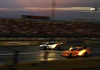 Zwei TF-Funny Cars bei einem Nightrace. Deut­lich sichtbar die sog. header flames