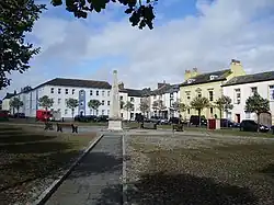 Dieses Farbfoto zeigt in einer etwas entfernten Frontaufnahme dem Fleming Square mit dem mittig auf dem Platz befindlichen Denkmal und den dahinter stehenden Häusern. Es wurde 2007 aufgenommen.,