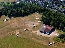 Luftaufnahme aus Süden: links oben bis mittig oben – das Wald- und Hügelgebiet: Lage der ehemaligen Königspfalz