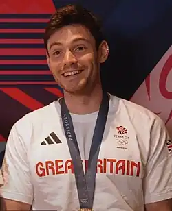 Freddie Davidson trägt ein weißes T-Shirt, seine olympische Bronzemedaille hängt an einem Band um seinen Hals.