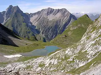 Freispitze (links), vor dieser der Jägerrücken und Saxerspitze (2690 m); im Vordergrund die Memminger Hütte mit ihren Hausberg, dem Seekogel (2412 m) und dem Unteren Seewisee, von Osten gesehen