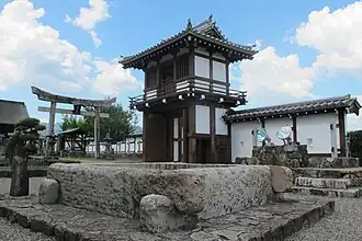 Tor, davor die steinerne Brunnenfassung