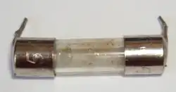 Gerätesicherung 5&nbsp;×&nbsp;20&nbsp;mm, zum Einlöten in Printplatten, nach Defekt. Rückstände des Schmelzdrahtes sind am Glaskolben zu sehen.