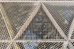 Gitterrostboden mit Wasserbecken, in dem sich das Gate spiegelt