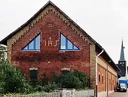 IHS als Klinker-Ornament in der Giebelmauer eines Wirtschaftsgebäudes