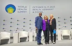 Dr. Githinji Gitahi, CEO von Amref Health Africa, steht gemeinsam mit Bundesministerin Schulze und mit Catherine Russel von UNICEF auf der Bühne des World Health Summit in Berlin