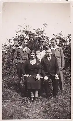 ein älteres Ehepaar sitzend, dahinter zwei junge Männer und ein junges Mädchen (Mire) stehend