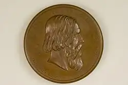 Das Foto zeigt die Vorderseite der bronzen Graefe-Medaille. In der Mitte ist Albert von Graefes Porträt im Profil mit Blick nach rechts erhaben geprägt. Es wird umrahmt mit dem in der oberen Hälfte am Rand in Versalien geprägten Namen „ALBRECHTVS • DE • GRAEFE“. Die untere Hälfte, abgesetzt von der oberen durch jeweils einem fünfzackigen Stern, zeigt die folgende Daten in römischer Ziffern „N • D • XXII • M • MAI • A • MDCCCXXVII • M • D • XX • M • IVL • A • MDCCCLXX“. Unterhalb des Halses befindet sich eine Signatur: „F. Hartzer FEC. E. Weigand SC“