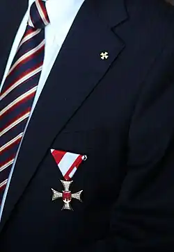 Das große Verdienstzeichen auf der Brust getragen sowie die Miniaturausführung am Kragen. Ausschnitt aus dem Porträt von Dr. Edwin Oberhauser (2014)