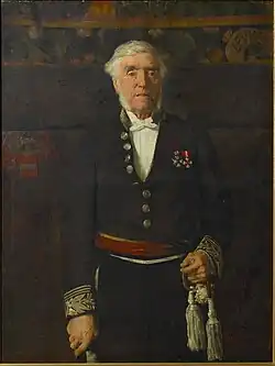 Portraitgemälde. Das Bild zeigt Leopold Vander Kelen als älteren, weißhaarigen Mann mit Backenbart. Er steht aufrecht und schaut den Betrachter an. Er trägt eine dunkle Uniform mit zwei Orden an der Brust. Seine rechte Hand stützt sich auf einen Stock, die linke ruht am Heft eines Schwertes. Der Hintergrund ist dunkel, man erkennt aber ein Wappen, den Schriftzug „LEUVEN“ sowie ein florales Muster am oberen Bildrand.