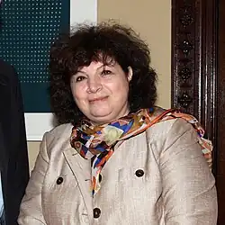 Gulnara Shahinian trägt eine helle Jacke und hat lockiges dunkles Haar.