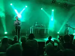 Zwei Musiker und eine Musikerin geben ein Konzert auf einer Bühne.