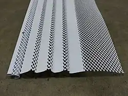 Ein Gutter Guard. Das linke Ende wird an der Außenseite der Rinne eingehakt.