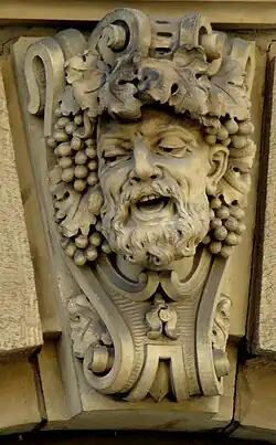 Bärtiges Gesicht mit Weintrauben und Weinlaub.