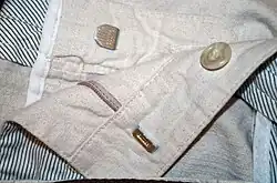 Metallfarbener Hosenhaken und Öse an einer hellen Herrenhose