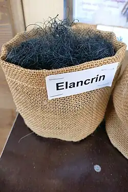 Foto eines groben Jutesäckchens das mit dunklen Fasern gefüllt ist. Ein Schild mit dem Schriftzug "Elancrin" ist daran festgetackert.