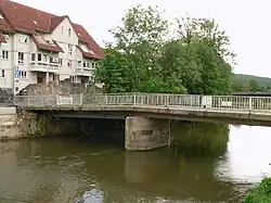 Die inzwischen abgerissene Löwenbrücke mit dem Standort des Brückenlöwen am Ufer im Bereich der Bäume, 2016
