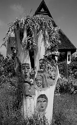 Ein Baumstumpf mit hinein geschnitzten Gesichtern von Hanns Mehner gestaltet