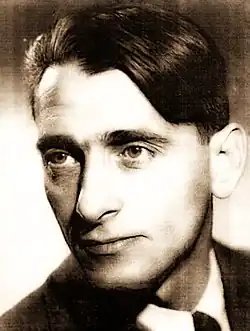 Das schwarz-weiß Foto zeigt Harry Brauner (1930). Er trägt einen dunklen Anzug mit Krawatte und ein weißes Hemd. Er hat kurzes, gekämmtes Haar.Der Stil des Bildes und der Kleidung deutet darauf hin, dass es sich um eine formelle oder offiziellen Anlass handeln könnte.