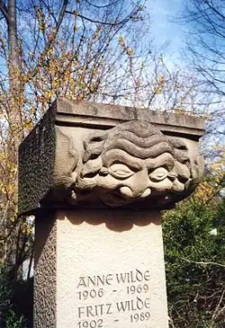 Der Maskenkopf stammt vom Alten Theater, wurde geborgen und diente als Grabstein für Anne und Fritz Wilde.