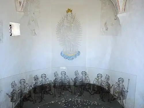 Blick in den Innenraum, am Boden Darstellung von Pilgern auf Plexiglas und eingeworfene Münzen