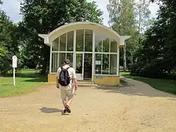 Mann mit Rucksack geht auf einen Glaspavillon mit Tonnendach zu