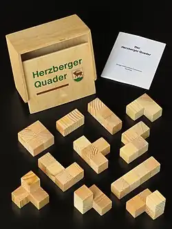 alle 11 Polywürfel mit dem Holzkästchen im Hintergrund