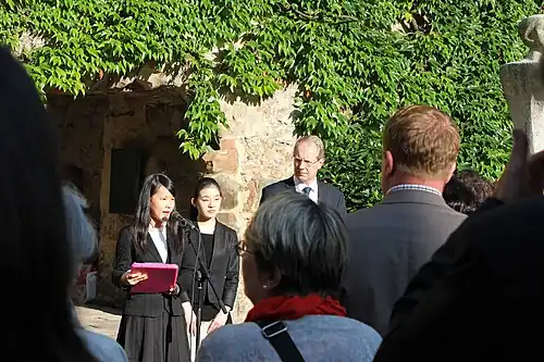 Friedenbotschafterinnen Aso Kokora (Nagasaki, am Mikrofon) und Hamasaki Fuko (Hiroshima, rechts neben ihr) halten eine Ansprache in der Aegidienkirche (2014)[73][74]