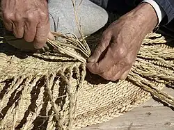 Handwerker, der einen Strohkorb flicht