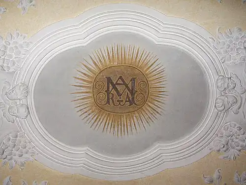 Einzig erhaltene barocke Stuckatur mit Deckenmalerei (Nordkapelle), die in einem Fresco ein Marienmonogramm zeigt.