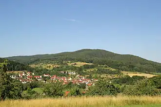 Die Hohe Mark (etwa Bildmitte) von Osten, mit dem Hauptgipfel des Hahnenkamms links hinten, dem Giftigen Berg rechts und dem Ort Brücken unterhalb.