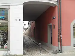 Durchgang eines Fußweges durch ein Haus. In der Mitte steht ein Poller.