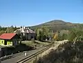 Stellwerk 2 und Eisenbahnerwohnhaus an der Spitze nach Ebersbach, im Hintergrund der namensgebende Berg Jedlová / Tannenberg (2018)