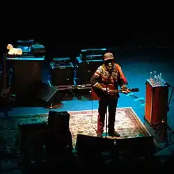 Jeff Mangum steht mit Gitarre auf einer Bühne am Mikrofon
