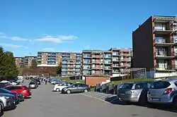 Foto von vielen baugleichen Wohnblöcken. Im Vordergrund parken viele Autos.