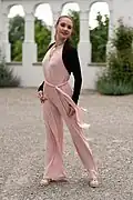 Jumpsuit mit plissierten Beinen. Oft ist das leichte Material unterfüttert oder wie hier mit hautfarbenem BH und Strumpfhose, um Durchscheinen zu vermindern.